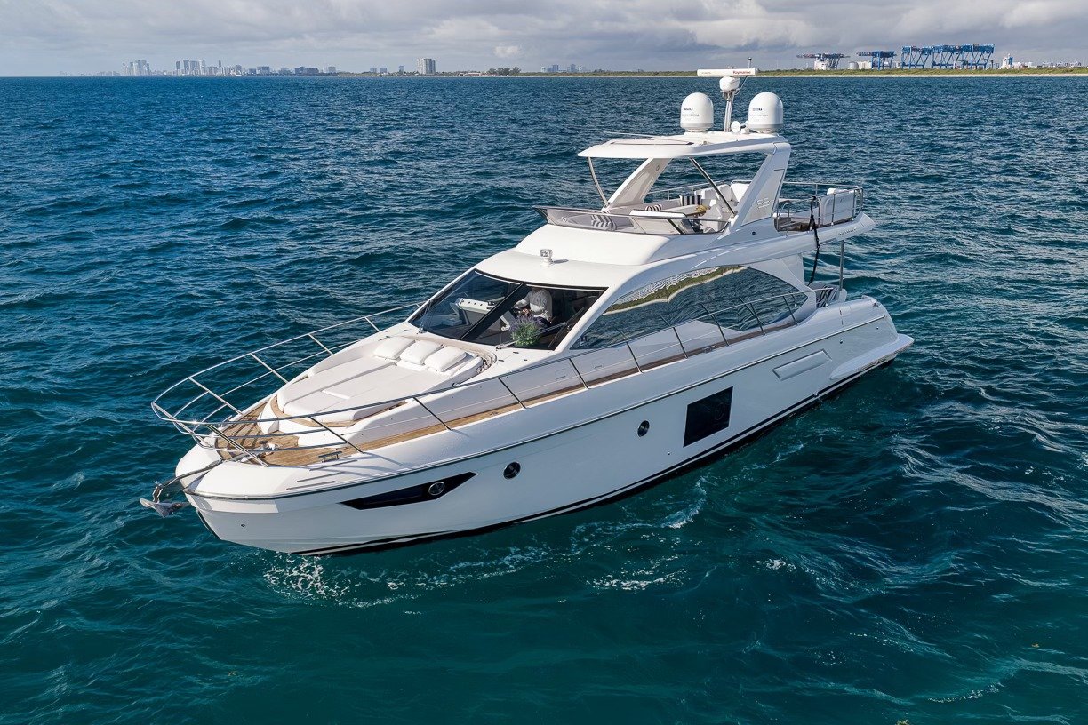 White motor yacht under way on blue water with a city skyline behind
